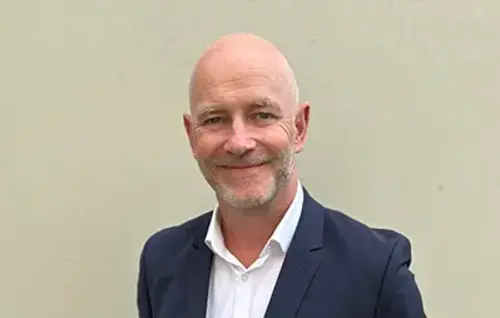 Gregor Zowierucha, CEO der PLATH GmbH & Co. KG, lächelt in die Kamera. Er trägt einen dunklen Anzug mit weißem Hemd. Der Hintergrund ist ein Büro.