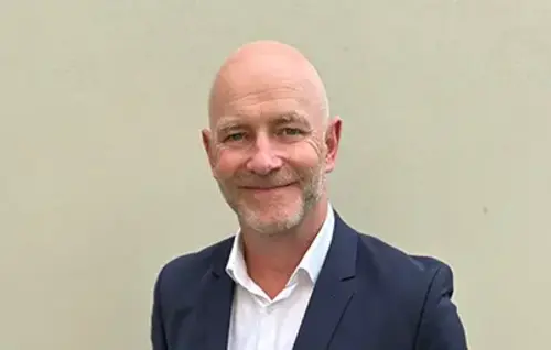 Gregor Zowierucha, CEO der PLATH GmbH & Co. KG, lächelt in die Kamera. Er trägt einen dunklen Anzug mit weißem Hemd. Der Hintergrund ist ein Büro.